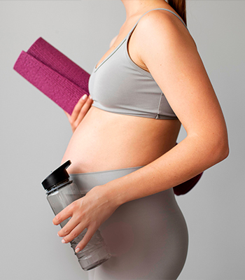 Gravid kvinna med yogamatta och vattenflaska