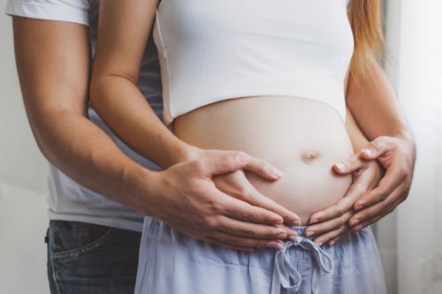 Man och kvinna som håller om gravid mage