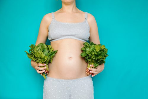 Gravid kvinna med två knippen sallad