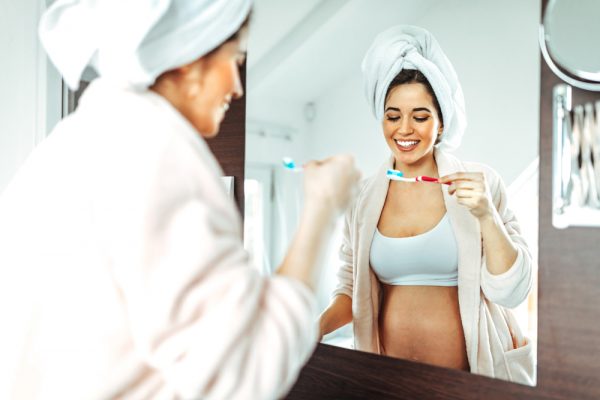 Gravid kvinna som borstar tänderna