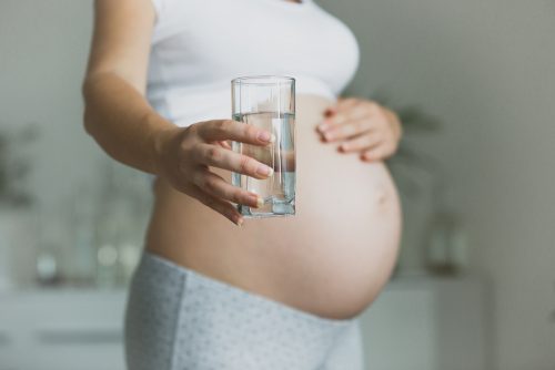 Gravid kvinna med ett glas vatten