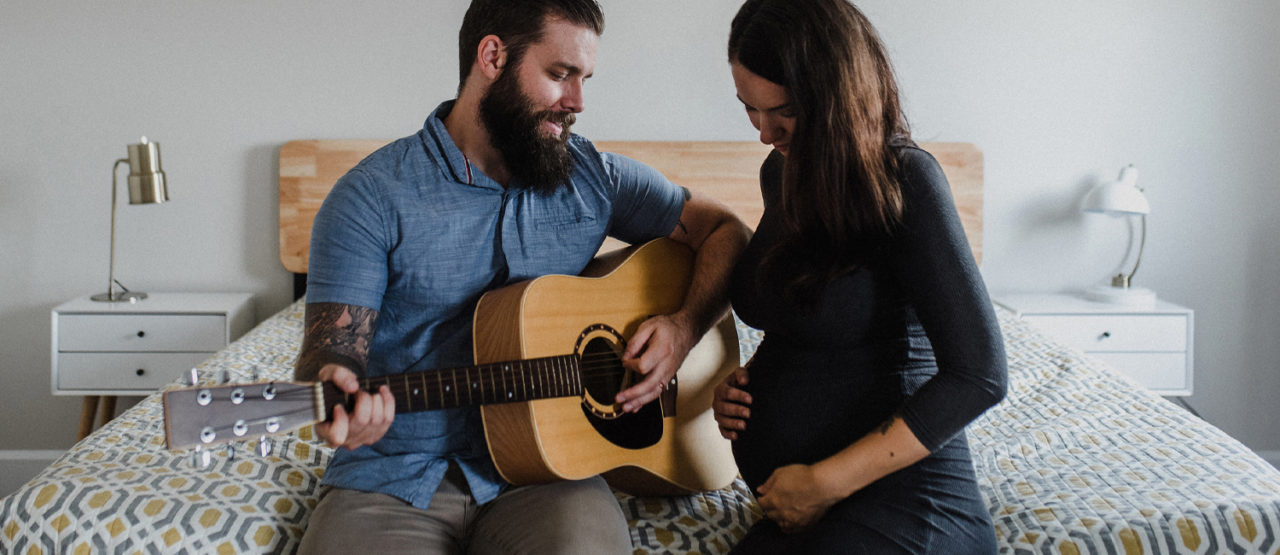 Gitarrspelande man och gravid kvinna