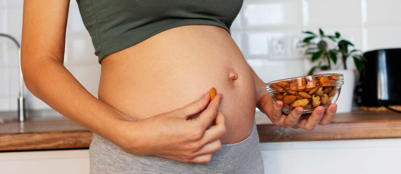 Gravid mage och en skål med nötter